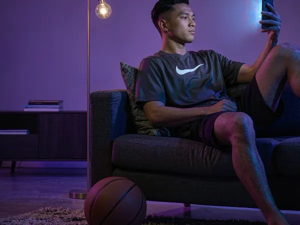 FG777 sports guide — man checking a smartphone with a basketball beside his chair